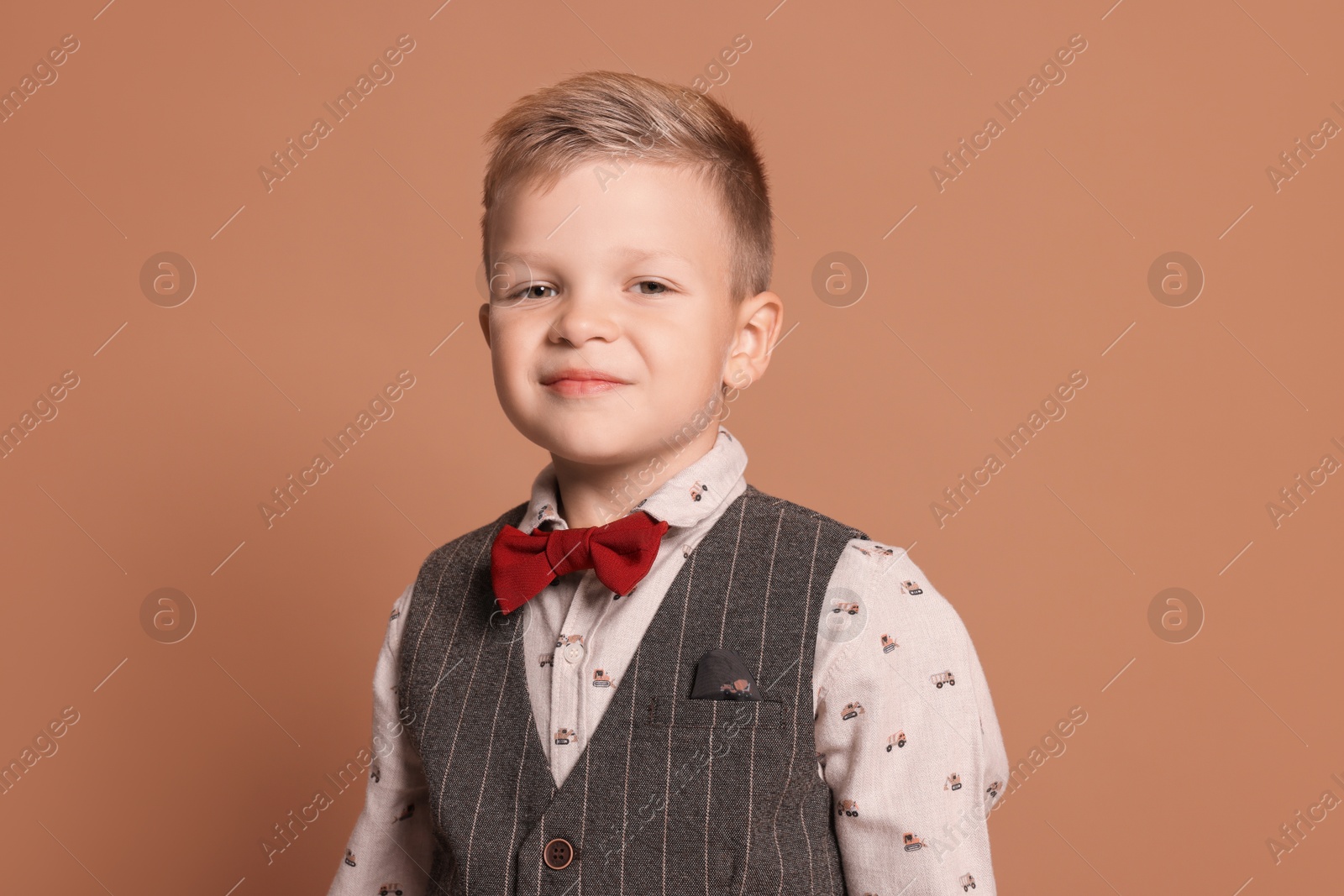 Photo of Portrait of little boy with stylish clothes on brown background