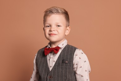 Portrait of little boy with stylish clothes on brown background