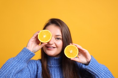 Photo of Happy young woman with halves of citrus fruit on orange background