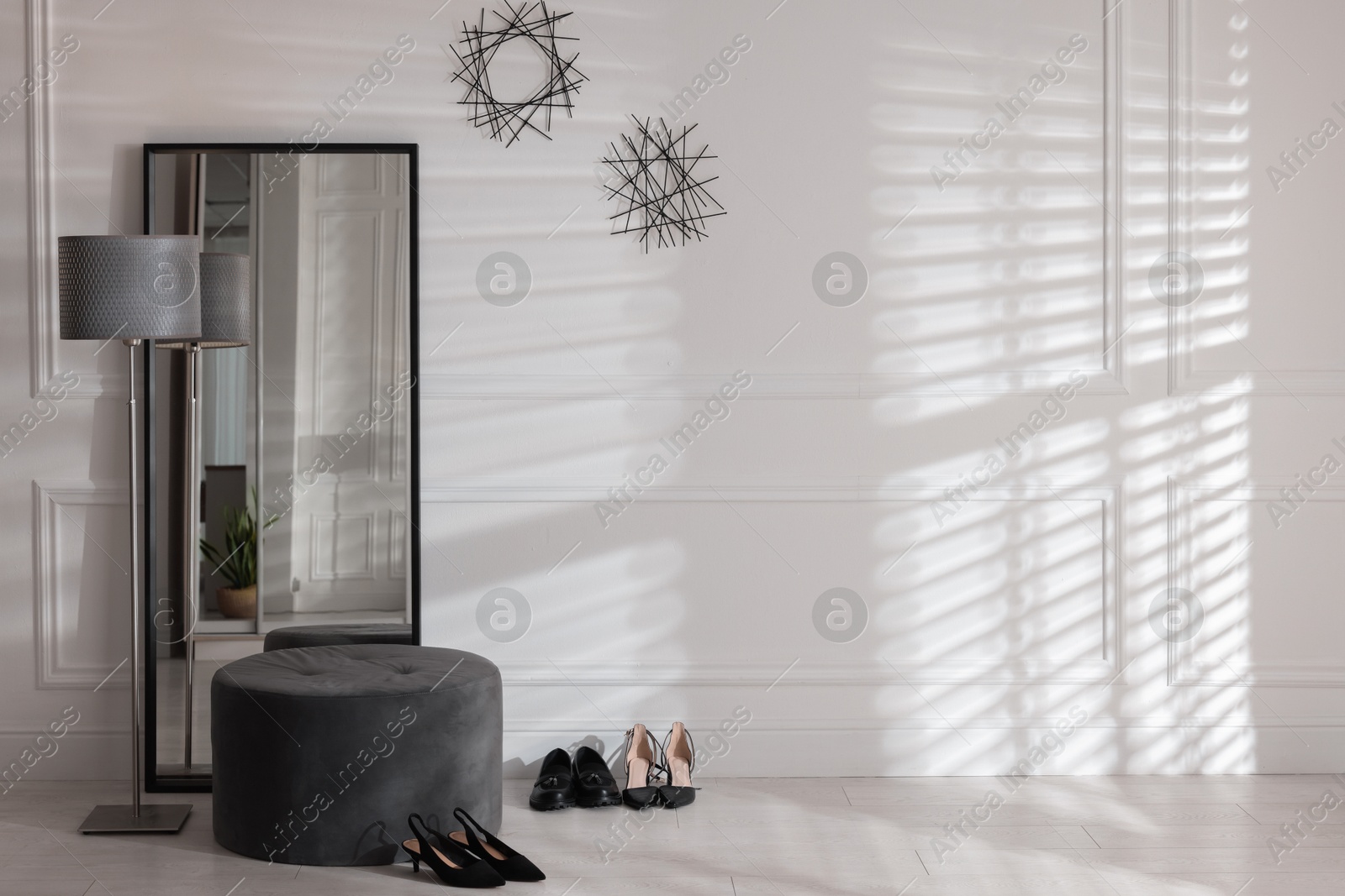 Photo of Stylish hallway interior with mirror, lamp and pouffe, space for text