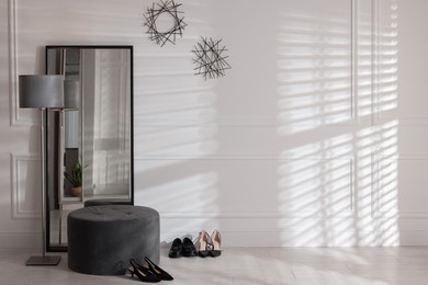 Photo of Stylish hallway interior with mirror, lamp and pouffe, space for text