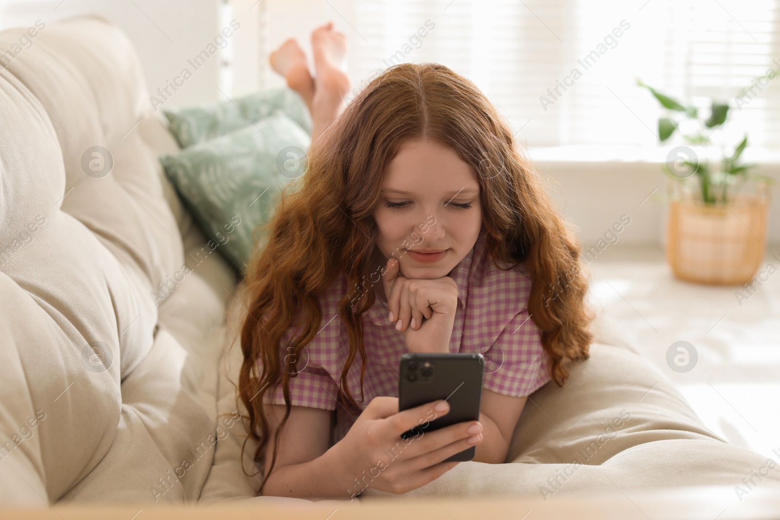 Photo of Beautiful teenage girl using smartphone on sofa at home