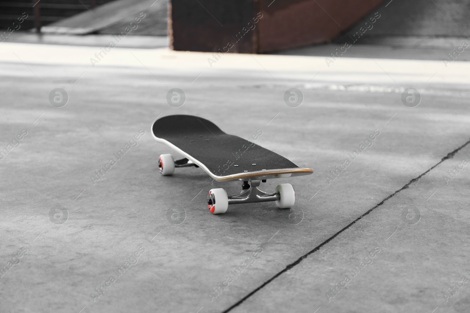 Photo of One modern skateboard with black griptape on ground outdoors