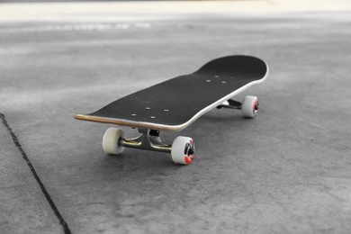 Photo of One modern skateboard on ground outdoors, closeup