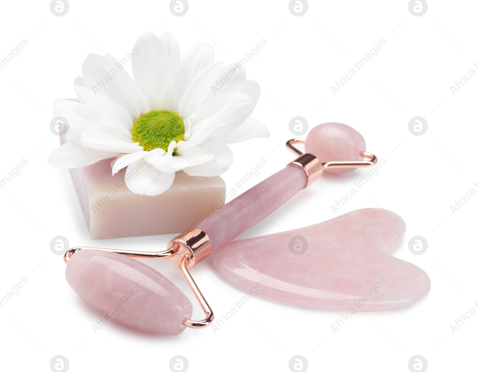 Photo of Face roller, soap, gua sha and flower isolated on white