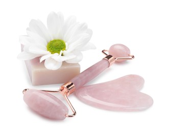 Face roller, soap, gua sha and flower isolated on white