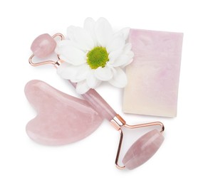 Face roller, soap, gua sha and flower isolated on white, top view