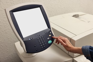 Photo of Woman using modern printer indoors, closeup. Printing house