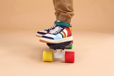 Photo of Little boy with skateboard on beige background, closeup