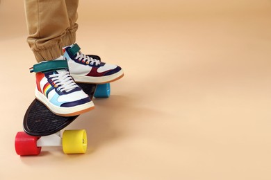 Photo of Little boy with skateboard on beige background, closeup. Space for text