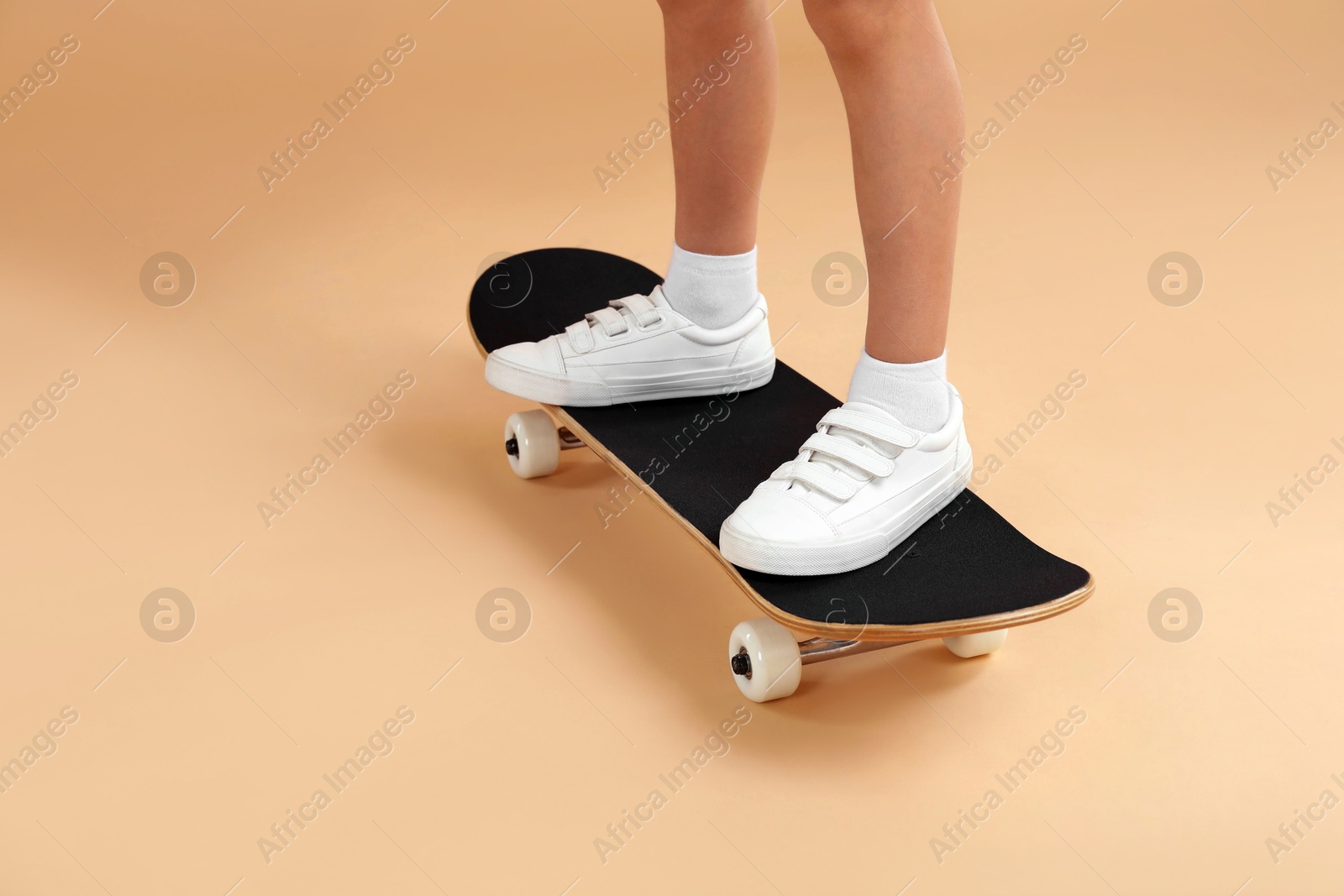 Photo of Little boy with skateboard on beige background, closeup