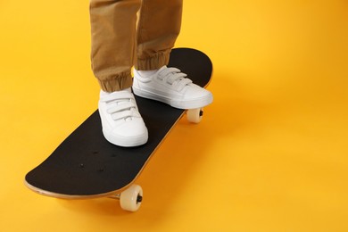 Photo of Little boy with skateboard on yellow background, closeup