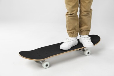 Photo of Little boy with skateboard on light grey background, closeup