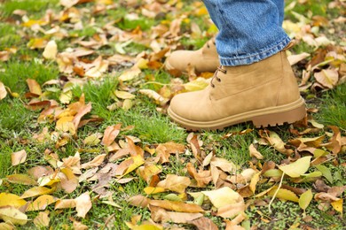 Photo of Man walking on green grass with fallen leaves, closeup. Space for text