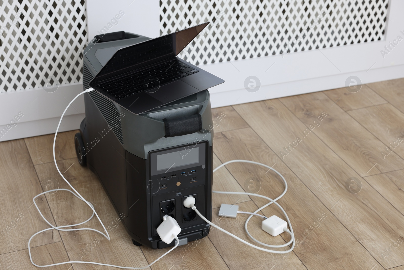 Photo of Modern portable power station, charging attached devices indoors, space for text