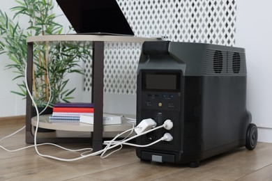 Photo of Modern portable power station, charging attached devices indoors