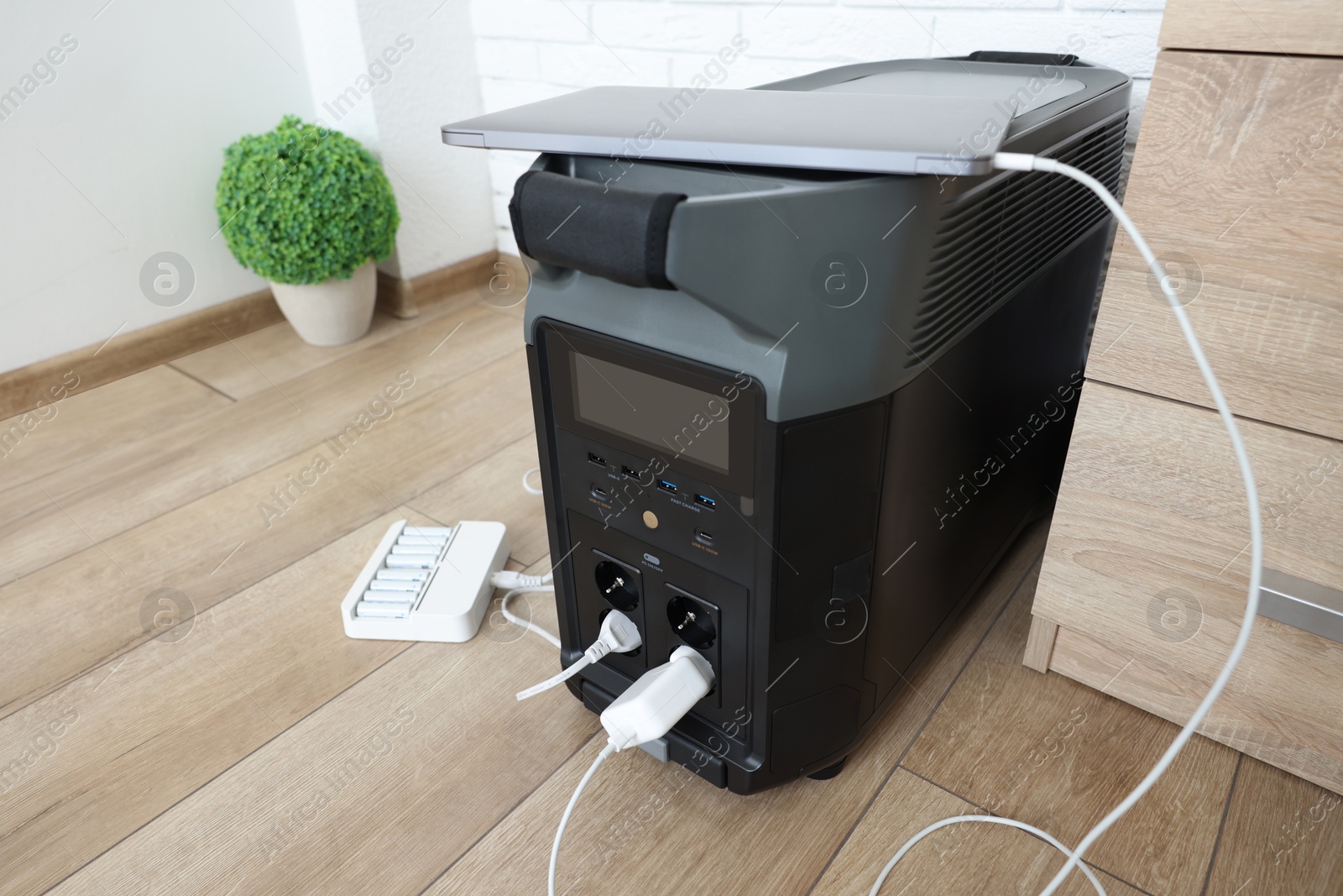 Photo of Modern portable power station, charging attached devices indoors