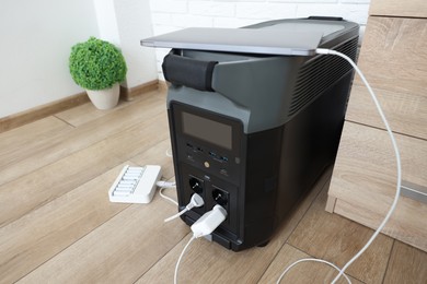 Photo of Modern portable power station, charging attached devices indoors