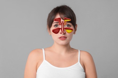 Woman suffering from sinusitis on light grey background. Illustration on her face showing disease