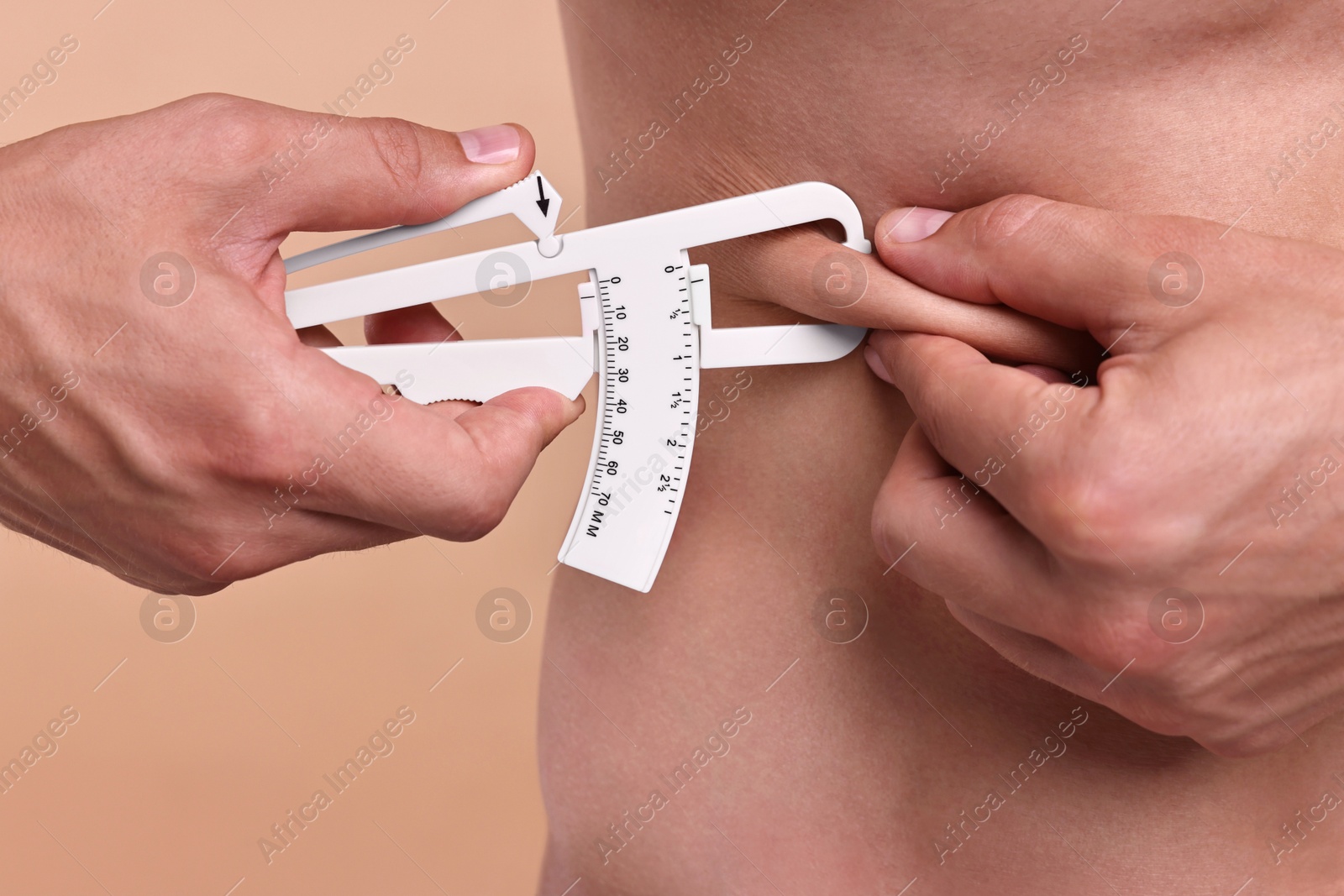 Photo of Man measuring body fat with caliper on beige background, closeup