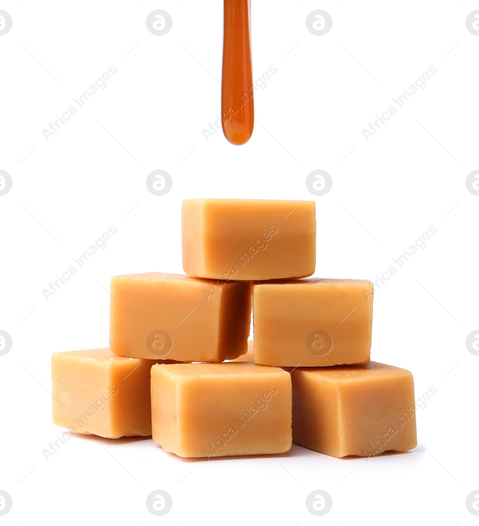 Photo of Caramel sauce dripping onto candies on white background, closeup