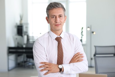 Photo of Portrait of middle aged man with crossed arms in office