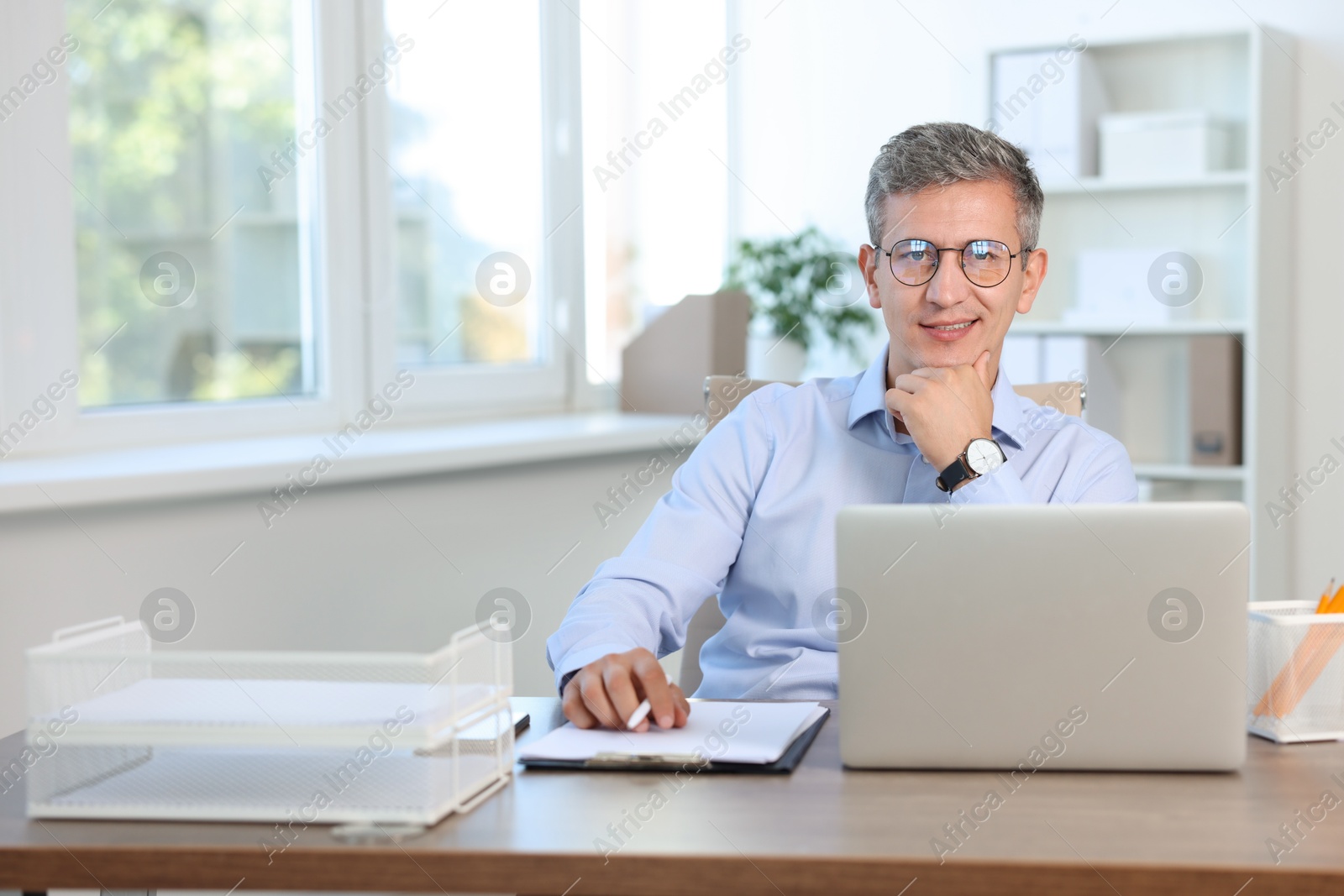 Photo of Portrait of smiling middle aged man at table in office