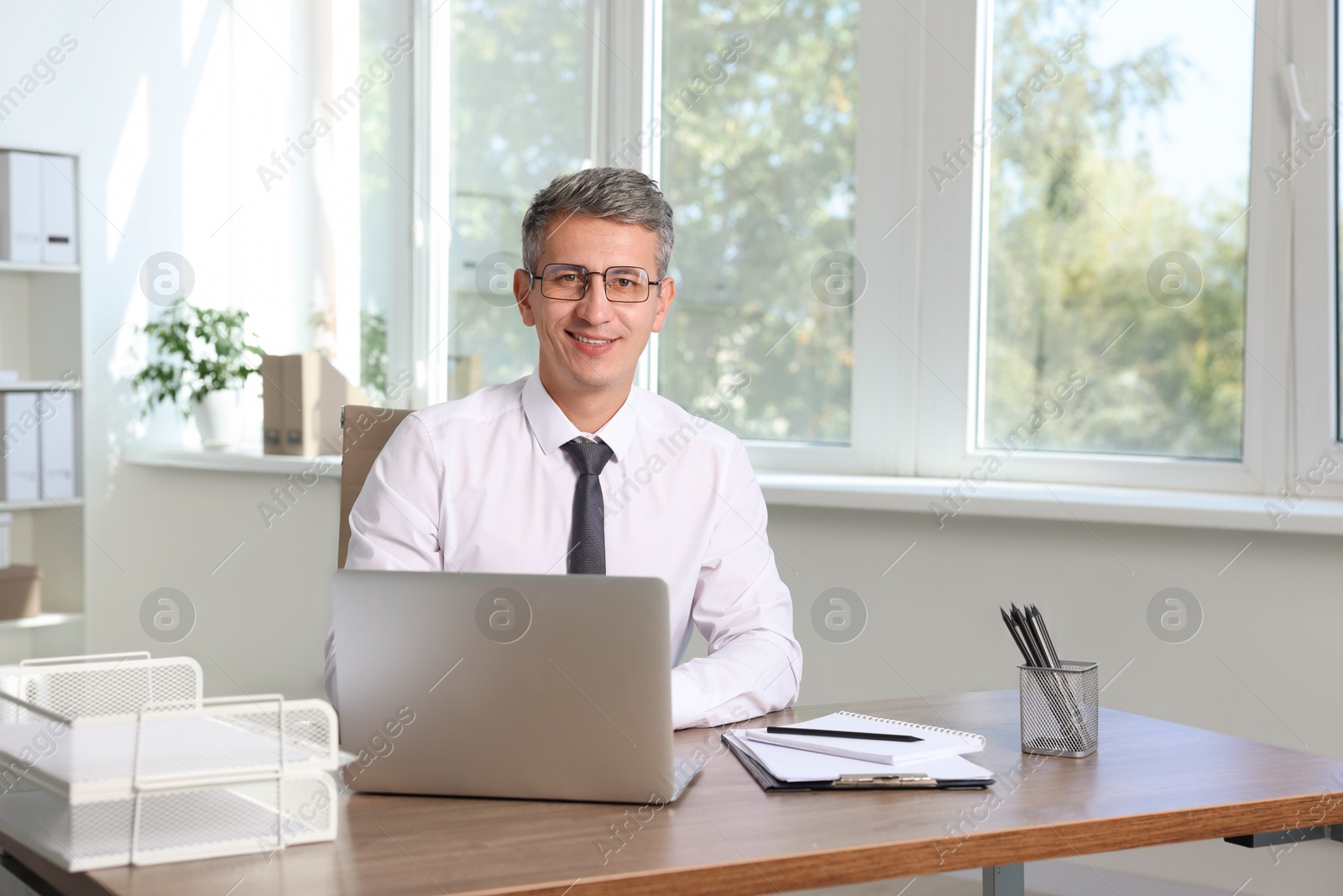 Photo of Portrait of smiling middle aged man at table in office