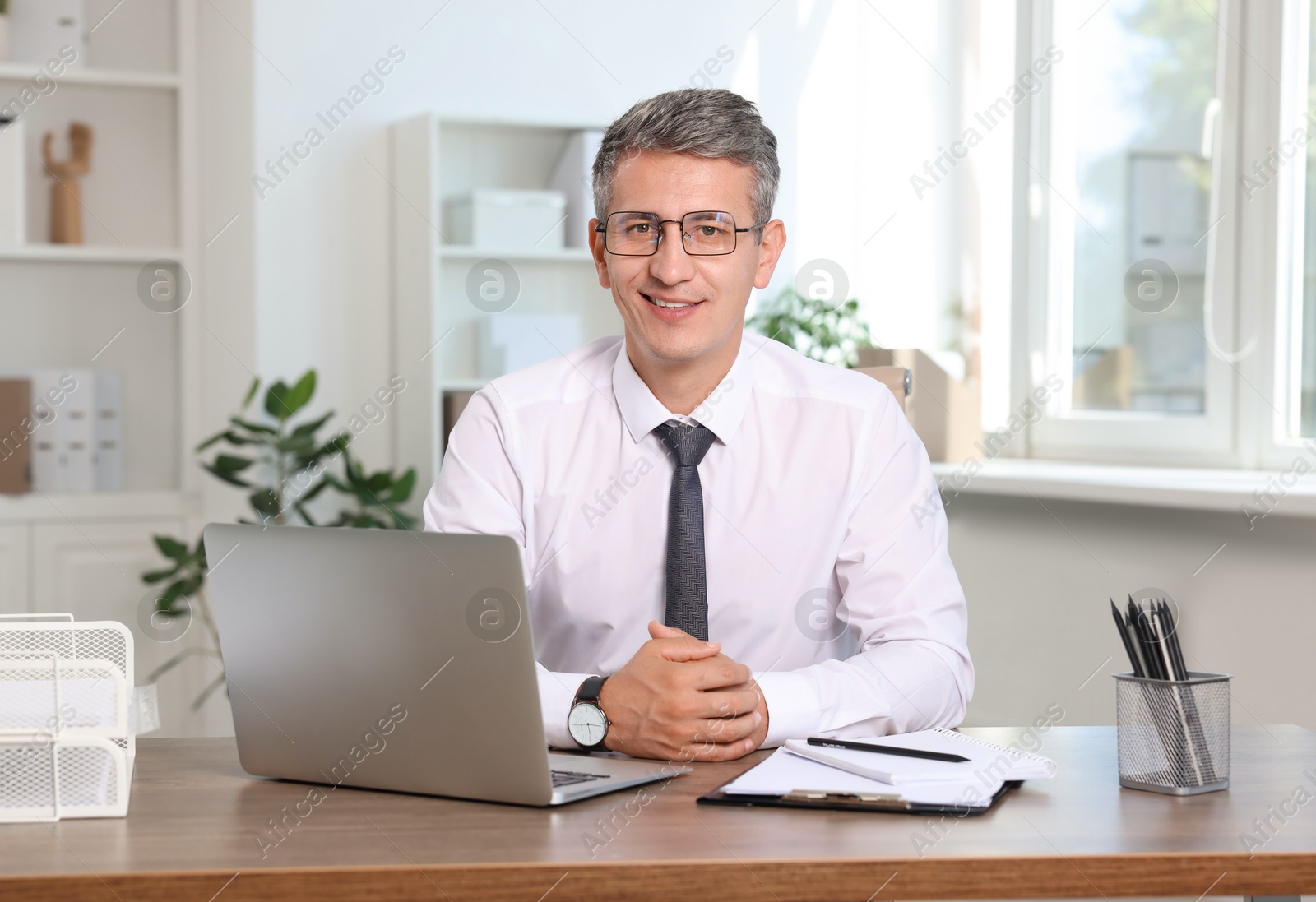 Photo of Portrait of smiling middle aged man at table in office