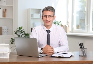 Portrait of smiling middle aged man at table in office