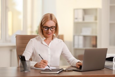 Photo of Smiling middle aged woman working at table in office