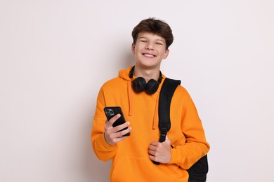 Photo of Teenage boy with headphones, smartphone and backpack on white background