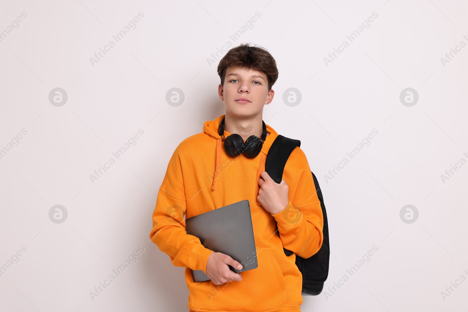 Photo of Teenage boy with headphones, laptop and backpack on white background