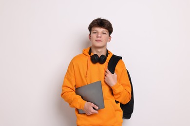 Photo of Teenage boy with headphones, laptop and backpack on white background