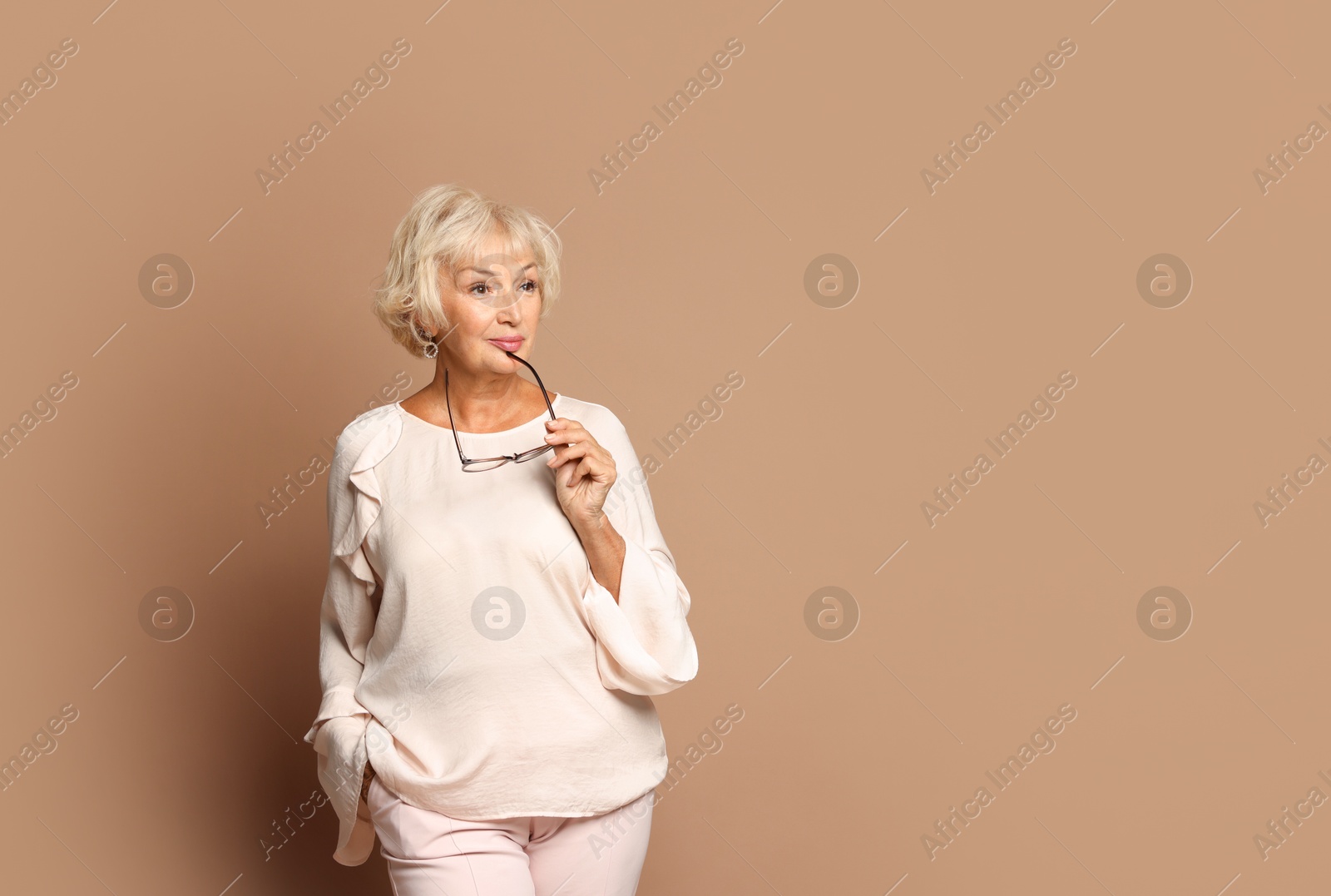 Photo of Portrait of beautiful senior woman on light brown background, space for text