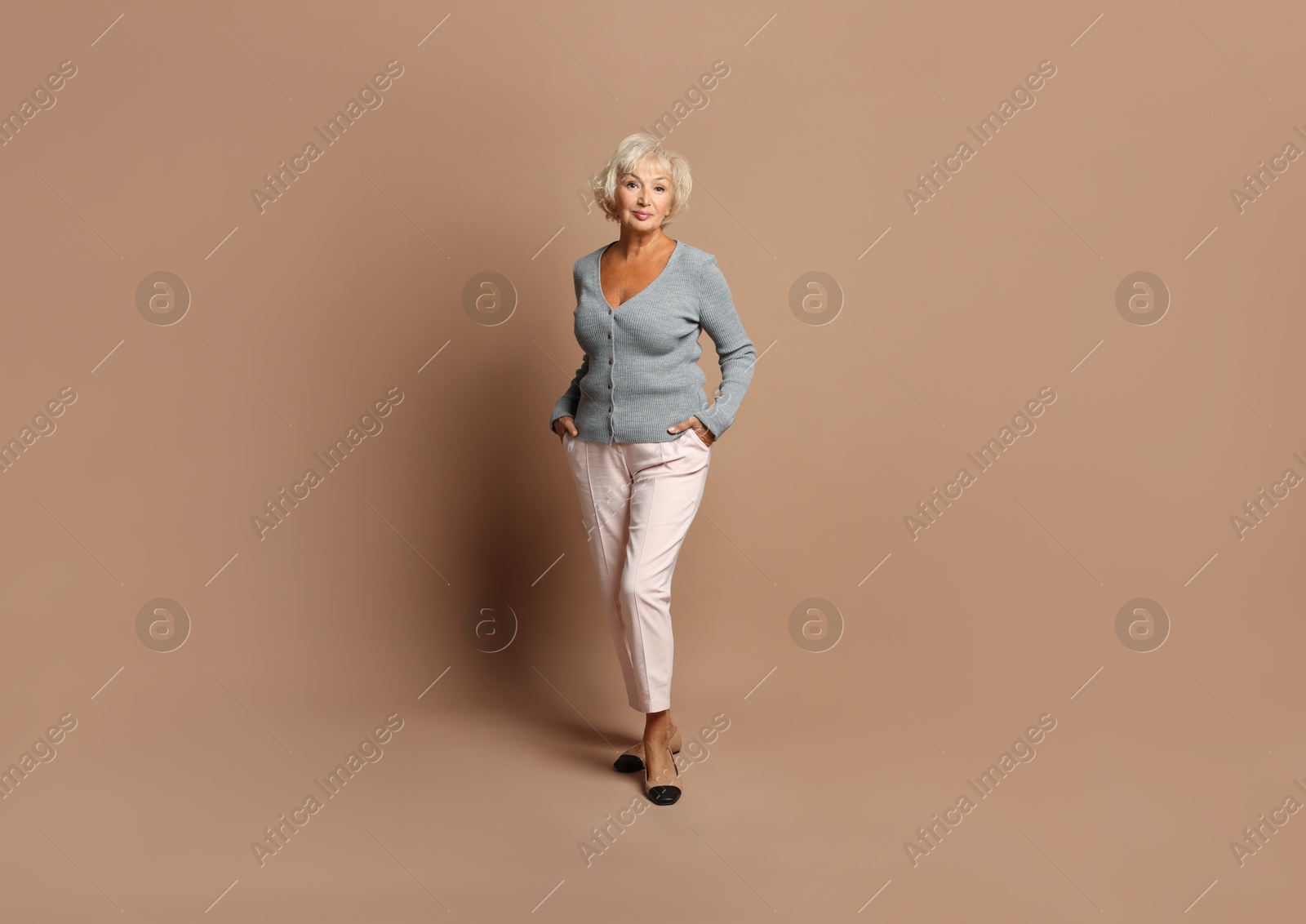 Photo of Full length portrait of beautiful senior woman on light brown background