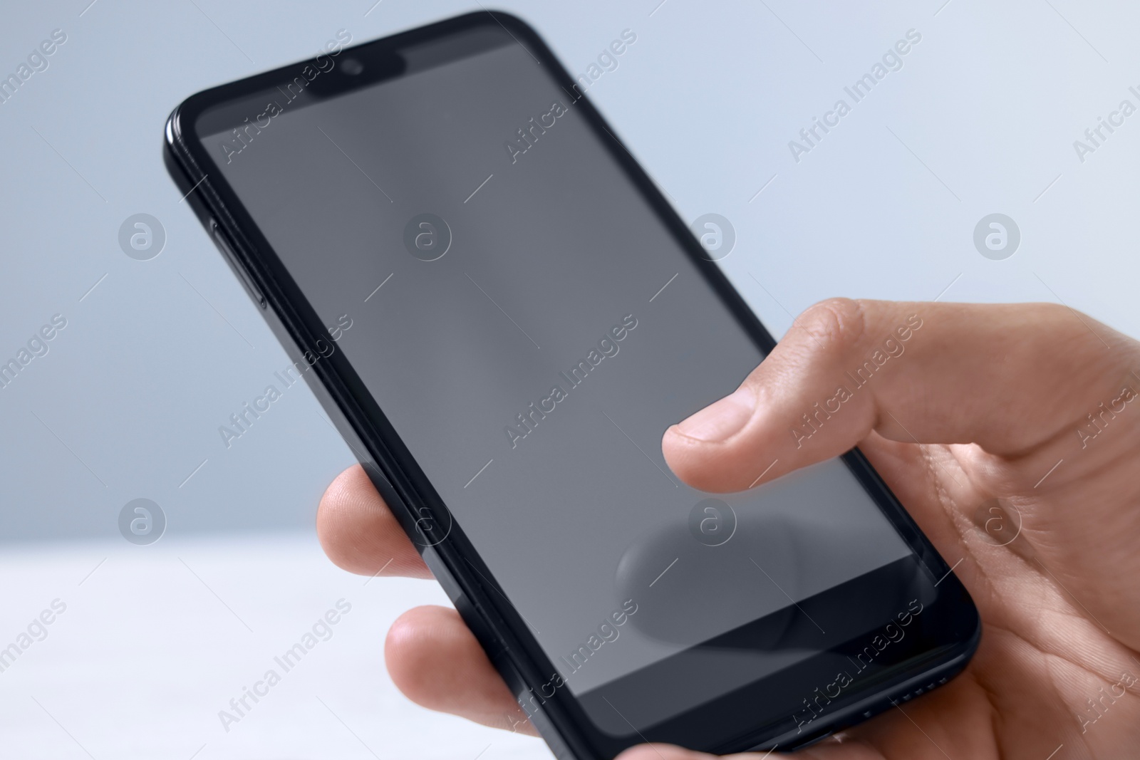 Photo of Man unlocking smartphone with fingerprint scanner on blurred background, closeup