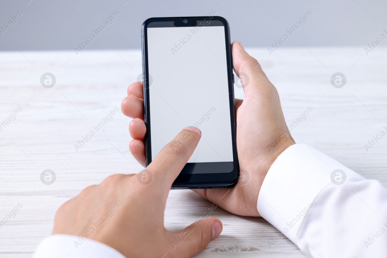 Photo of Man unlocking smartphone with fingerprint scanner at light wooden table, closeup