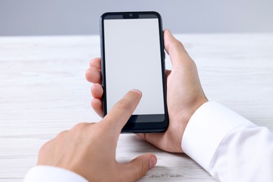 Photo of Man unlocking smartphone with fingerprint scanner at light wooden table, closeup