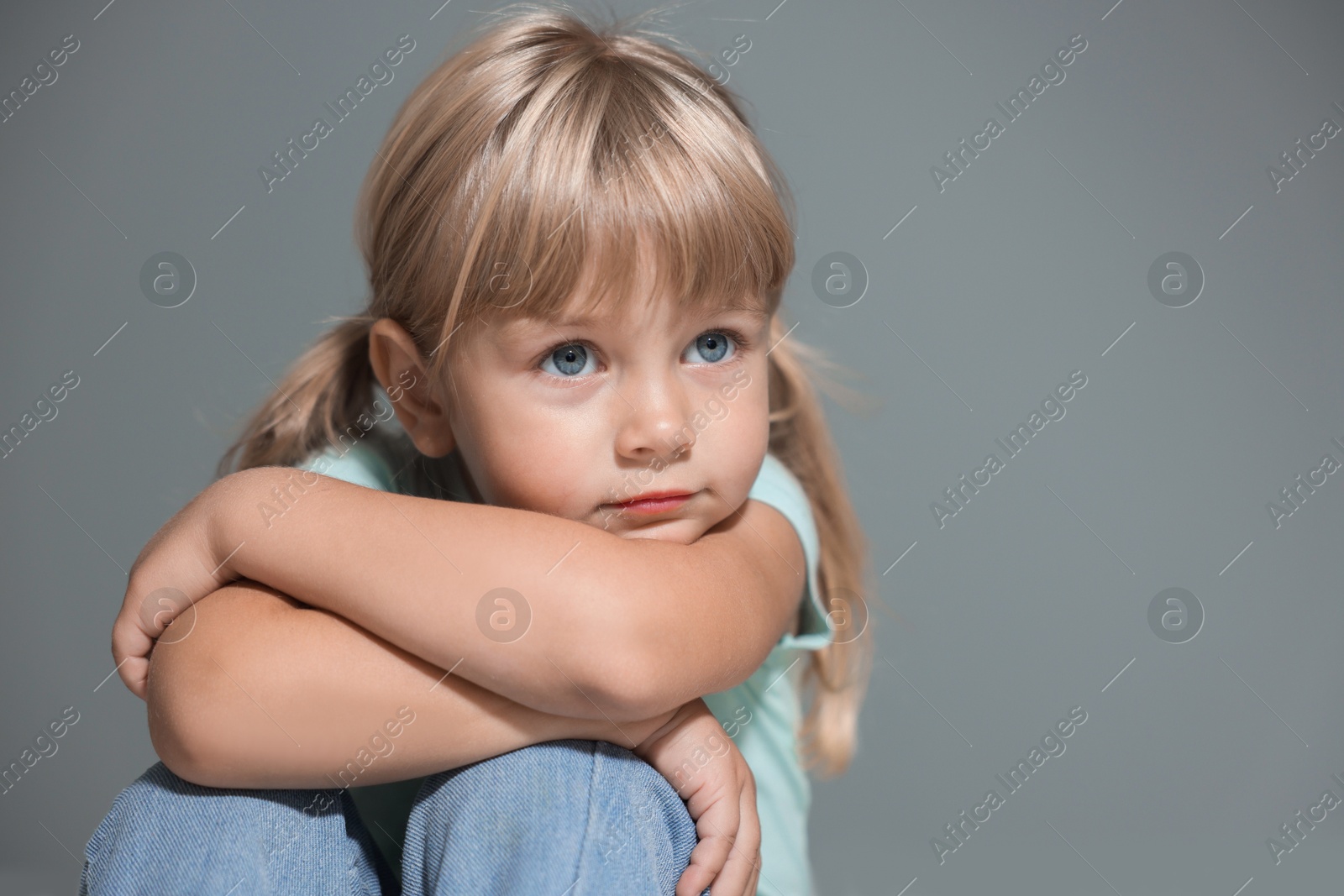 Photo of Orphanage concept. Sad little girl on grey background, space for text