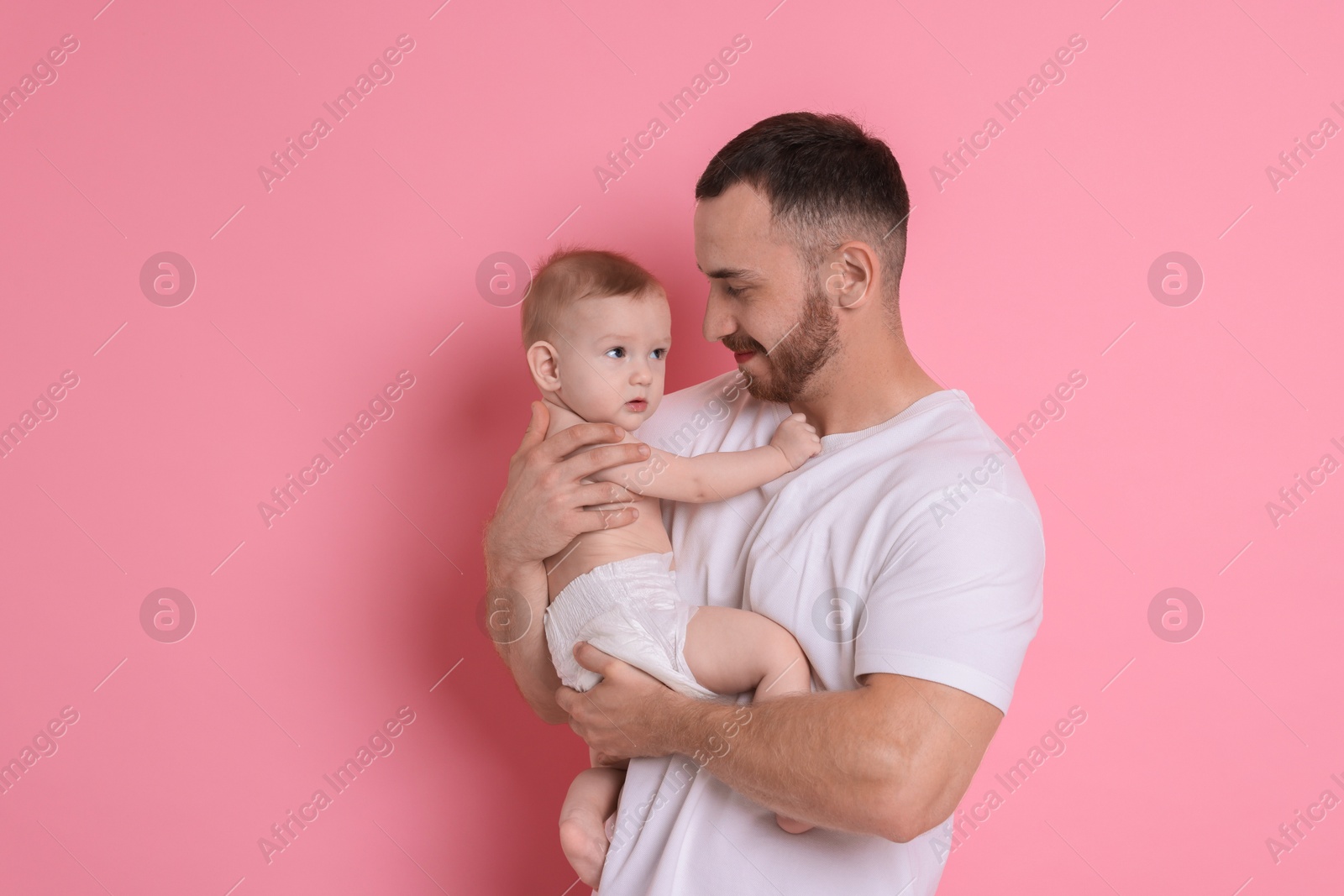 Photo of Father with his cute baby on pink background