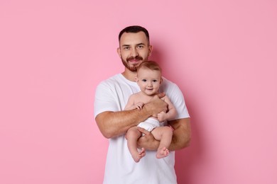 Photo of Father with his cute baby on pink background