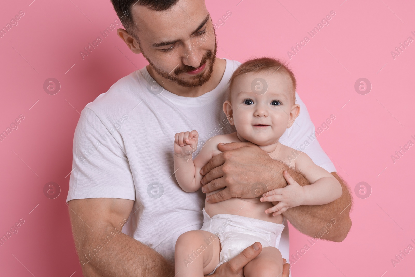 Photo of Father with his cute baby on pink background