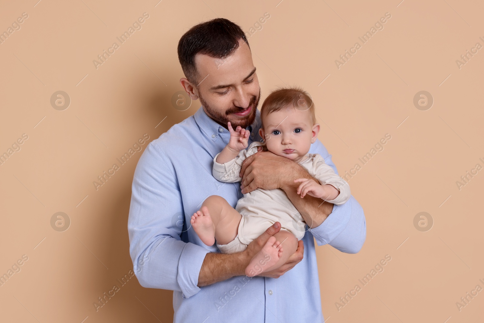 Photo of Father with his cute baby on beige background