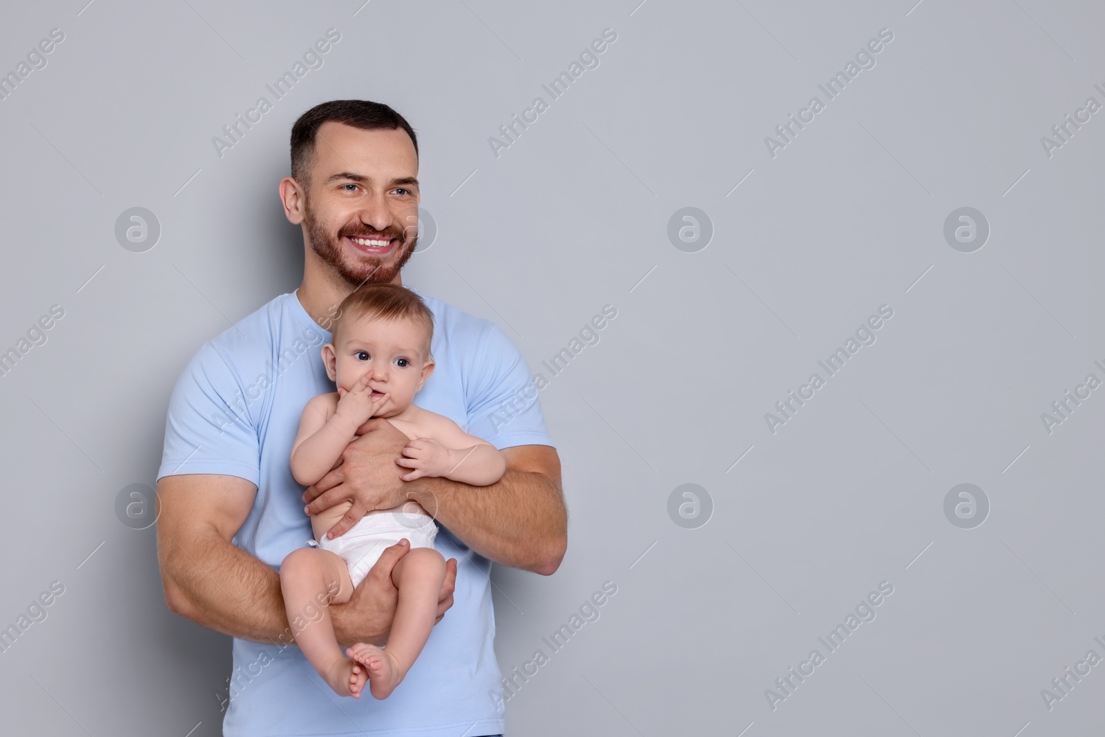 Photo of Father with his cute baby on grey background, space for text