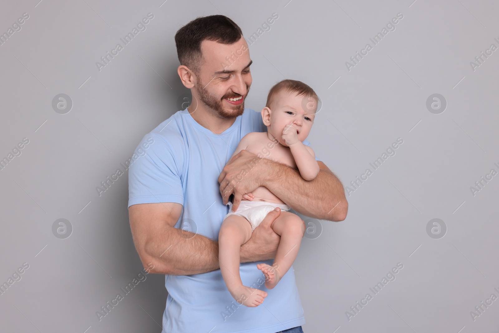 Photo of Father with his cute baby on grey background