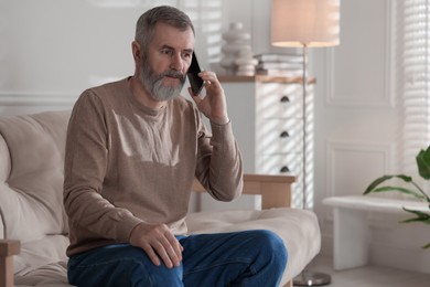 Photo of Senior man talking on smartphone at home