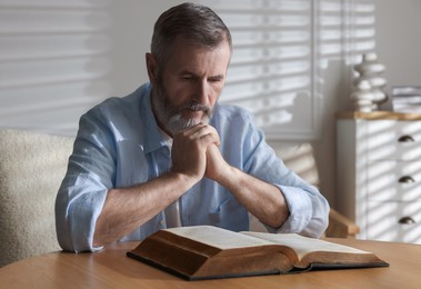 Photo of Senior man reading book at table indoors