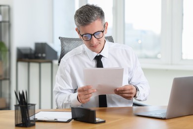 Photo of Businessman with documents at table in office