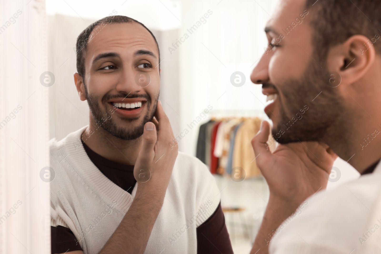 Photo of Smiling man looking at mirror at home